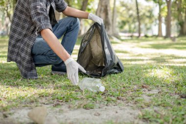 Adamın elleri plastik şişeleri topluyor, çöpleri siyah çöp torbalarına doldurup parkları temizliyor, kirlilikten kaçınıyor, çevreye ve ekosisteme dost oluyor..