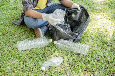 Çöp toplama, insanların elleri plastik şişeleri toplar, çöpleri parkları temizlemek, kirlilikten kaçınmak, çevreye ve ekosisteme dost olmak için siyah çöp torbalarına koyar..