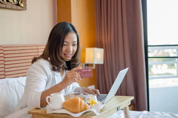 여성은 카드를 방에서 과일로 침대에서 휴식을 취하며 온라인 인터넷 결제를 — 스톡 사진