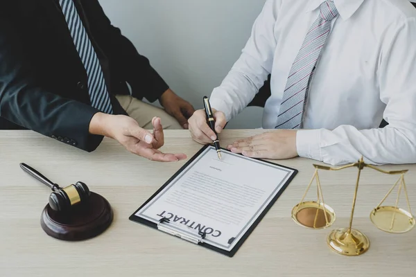 Bir erkek avukat ya da yargıç müvekkillerine adalet ve kovuşturma konusunda danışmanlık yapıyor. Teraziler, yargıç tokmağı, yasal belgeler, yasal hizmetler kavramı..