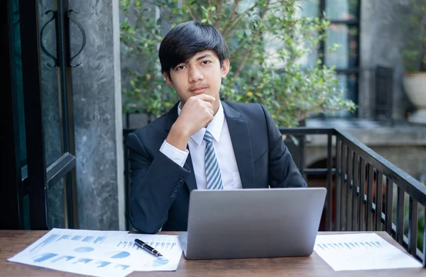 Genç Asyalı iş adamı finansal piyasa analisti masalarında oturuyor ve başarılı iş büyüme sürecini planlayan yatırımlarının sonuçlarını gösteren mali grafikleri hesaplıyor..