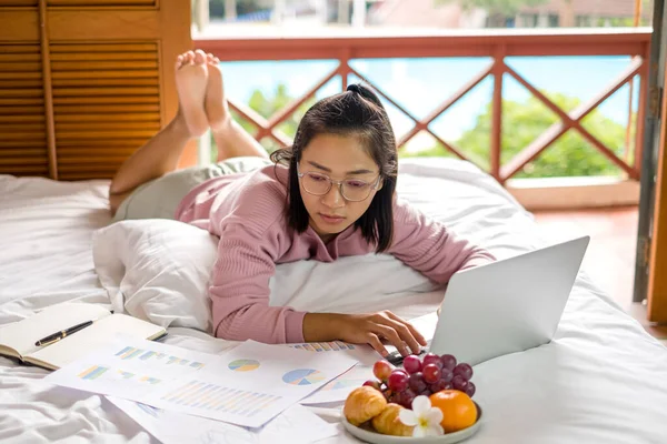 work from home, a young Asian woman who works in finance at home calculates financial graphs showing the results of his investments, planning the steps of his business growth.