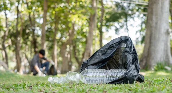 Plastic bottle. young Asian men pick up plastic bottles, put garbage in black garbage bags to clean up at parks, avoid pollution, be friendly to the environment and ecosystem.