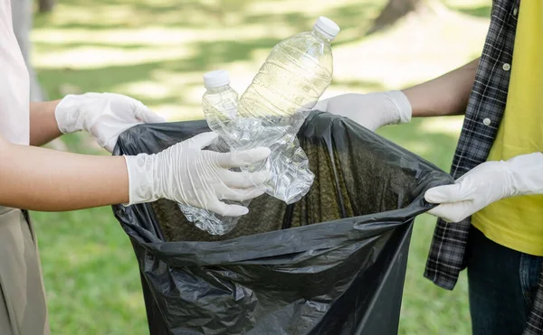 garbage collection, volunteer team pick up plastic bottles, put garbage in black garbage bags to clean up at parks, avoid pollution, be friendly to the environment and ecosystem.