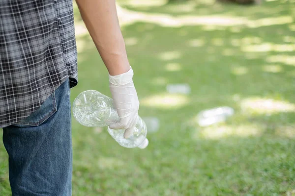 Garbage collection, Man\'s hands pick up plastic bottles, put garbage in black garbage bags to clean up at parks, avoid pollution, be friendly to the environment and ecosystem.