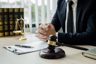 Profesyonel erkek avukatlar bir hukuk bürosunda çalışır. Teraziler, adalet terazileri, yargıç tokmağı ve dava belgeleri vardır. Hukuk ve adalet kavramları.