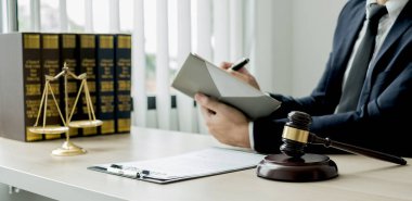 Profesyonel erkek avukatlar bir hukuk bürosunda çalışır. Teraziler, adalet terazileri, yargıç tokmağı ve dava belgeleri vardır. Hukuk ve adalet kavramları.