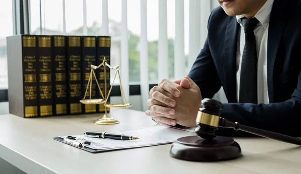 Profesyonel erkek avukatlar bir hukuk bürosunda çalışır. Teraziler, adalet terazileri, yargıç tokmağı ve dava belgeleri vardır. Hukuk ve adalet kavramları.