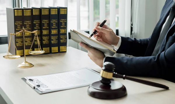 Profesyonel erkek avukatlar bir hukuk bürosunda çalışır. Teraziler, adalet terazileri, yargıç tokmağı ve dava belgeleri vardır. Hukuk ve adalet kavramları.