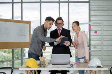 Erkek ve kadın mühendisler ve mimarlardan oluşan bir ekip, çalışma ekibi, inşaat planlarını tartışıyor ve çiziyor, baskı yapıyor, inşaat alanlarında yazıyor..