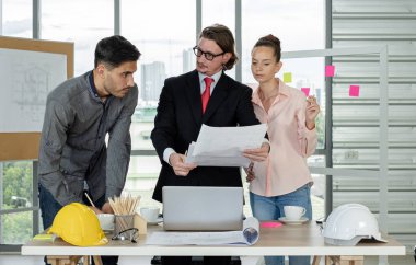 Erkek ve kadın mühendisler ve mimarlardan oluşan bir ekip, çalışma ekibi, inşaat planlarını tartışıyor ve çiziyor, baskı yapıyor, inşaat alanlarında yazıyor..