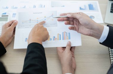 İki iş lideri çizelgeler, finansal grafikler hakkında konuşuyor. Sonuçları gösteren planlama stratejilerini analiz ediyor ve hesaplıyor. Ticari başarı oluşturma süreçlerini de..