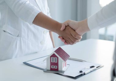 İş adamları ve emlakçılar ev sigortası ve sözleşme imzalama görüşmelerini tamamladıktan sonra el sıkışıyorlar. Ev sigortası kavramı.