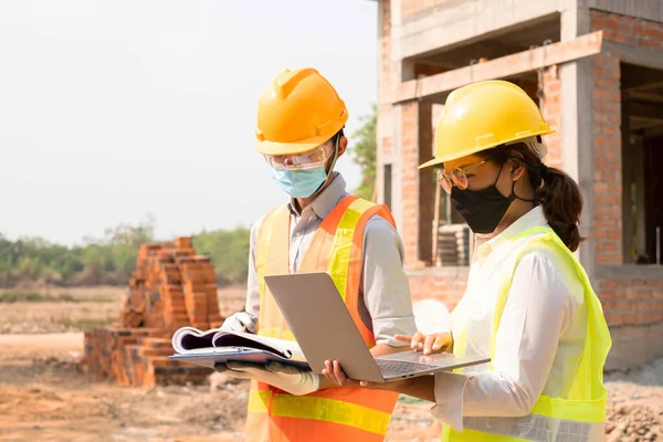 A team of male and female engineers or architects is exploring and inspecting the outdoor construction site work.