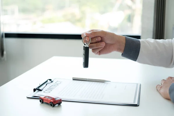 Car dealer businessman holding a car key. Car loan and insurance concept.