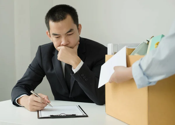 Desperately fired female office worker employee hands her employer her resignation letter and packs her belongings in a cardboard box concept dismissal and unemployment.