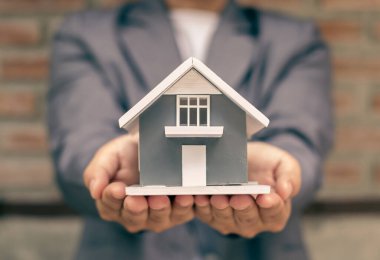 Ev sigortası ve gayrimenkul. Ev modelini elinde tutan iş kadını ev kiralama, ev satın alma ve ev sigortası için yatırım yapıyor..