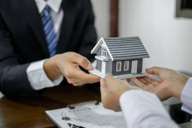 Emlakçı, kira sözleşmesini imzalayıp ev sigortasını resmen tamamladıktan sonra evi yeni sahibinin müşterisine verir. Kiralama ve sigorta kavramları.