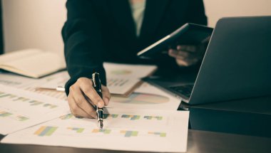 İş kadını eli masalarında oturur ve başarılı iş büyümesi sürecini planlayan yatırımlarının sonuçlarını gösteren mali grafikleri hesaplar.