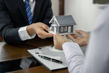 Emlakçı, kira sözleşmesini imzalayıp ev sigortasını resmen tamamladıktan sonra evi yeni sahibinin müşterisine verir. Kiralama ve sigorta kavramları.