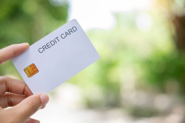 Kredi Kartı. Çevrimiçi alışveriş ve ödemeler için yeşil doğaya sahip el ele tutuşan kredi kartı ve kopyalama alanı kavramı.