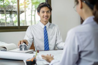 Erkek ve kadın mühendisler ve mimarlardan oluşan bir ekip, iş görüşmeleri, inşaat ve ev tasarımı projeleri hakkında tartışmalar. Ev tasarımı kavramı.