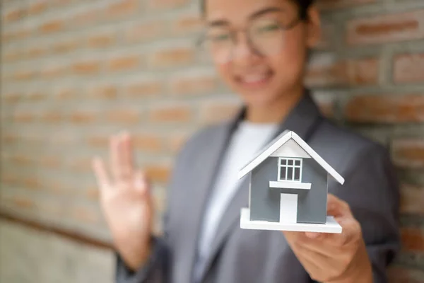 Home insurance concept and real estate. Businesswoman holding a house model working in investment about renting a house, buying a house, and home insurance.