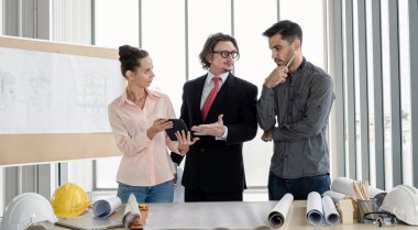 Erkek ve kadın mühendisler ve mimarlardan oluşan bir ekip, çalışma ekibi, inşaat planlarını tartışıyor ve çiziyor, baskı yapıyor, inşaat alanlarında yazıyor..