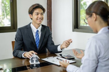 Ev modeli olan bir emlakçı ev sigortası almak için müşterilerle konuşuyor. Ev sigortası kavramı.