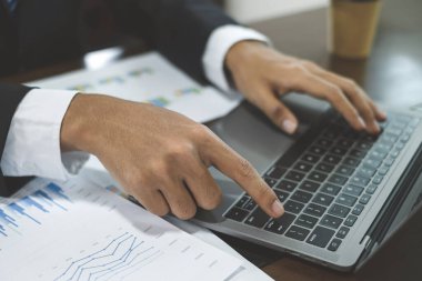 Genç Asyalı iş adamı finansal piyasa analisti masalarında oturuyor ve başarılı iş büyüme sürecini planlayan yatırımlarının sonuçlarını gösteren mali grafikleri hesaplıyor..