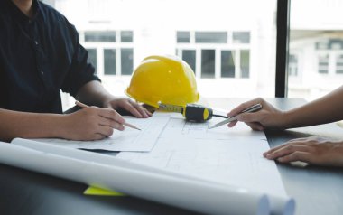 Mühendisler ve mimarlardan oluşan bir ekip, çalışma ekibi, toplantı, inşaat planları ve çizim planları, baskı, inşaat alanlarında yazma konuları. Ev tasarımı kavramı.