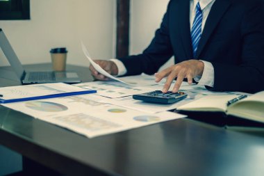 Genç Asyalı iş adamı finansal piyasa analisti masalarında oturuyor ve başarılı iş büyüme sürecini planlayan yatırımlarının sonuçlarını gösteren mali grafikleri hesaplıyor..