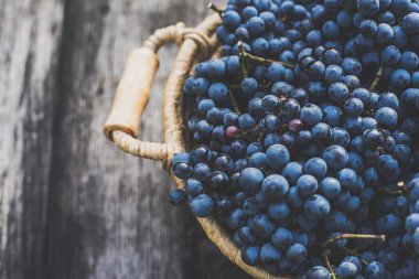 Tahta masadaki sepetin üzerinde üzümler