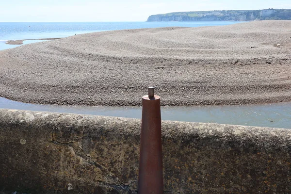 A metal bollard by the breakwater at the mouth of the river Axe near Axmouth in Devon.