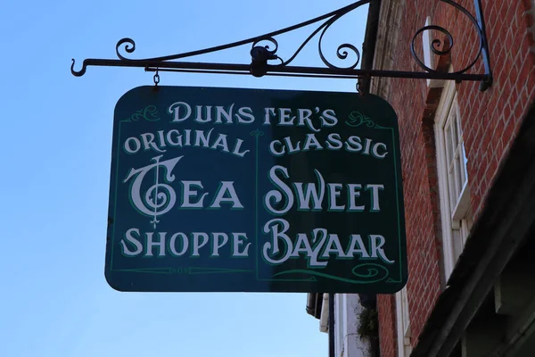 The hanging sign outside a tea shop and sweet bazaar in the High Street of Dunster in Somerset, England