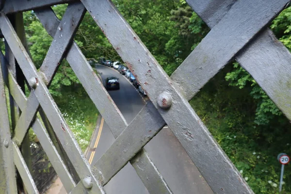 A view of the road through a rusty metal lattice bridge in Topsham in Devon, England