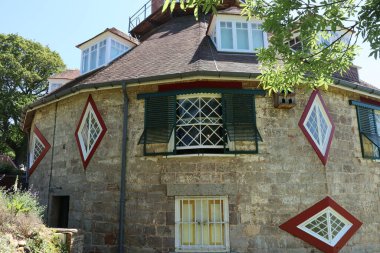 the strange shape of windows of an unusual historic sixteen sided house on a beautiful sunny summers day in Devon, England