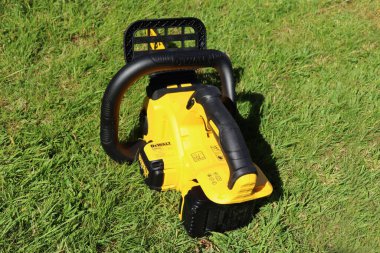 EXETER, DEVON, ENGLAND - JUNE 15TH 2021: Dewalt 18 volt cordless chainsaw on the lawn