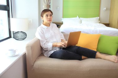 Genç bayan serbest yazar odasında kanepede çalışıyor. 