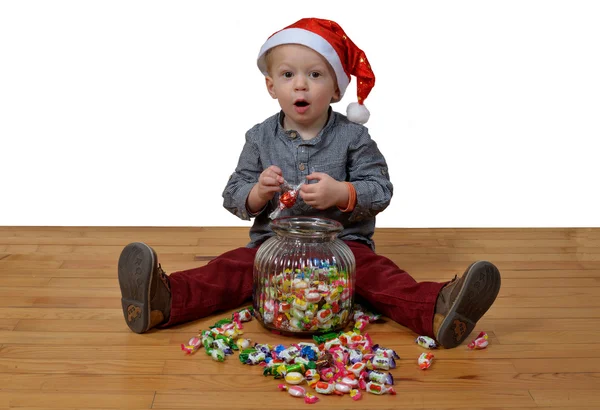 Bebé con sombrero de santa comer un montón de dulces — Foto de Stock