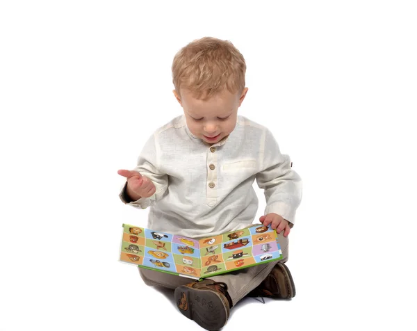Bebé sentado con las piernas cruzadas leyendo un libro — Foto de Stock