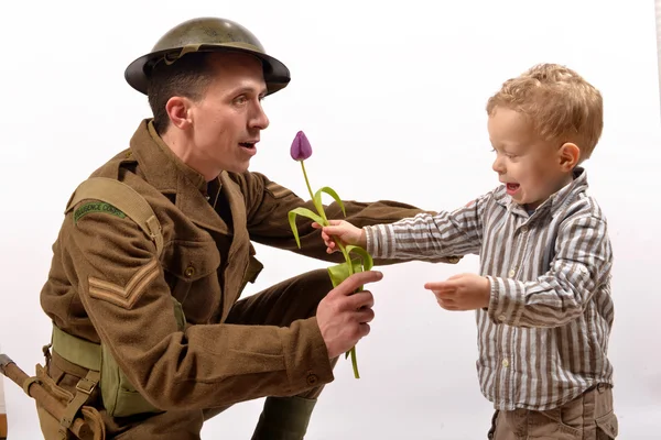 Un niño pequeño le da una flor a un soldado británico — Foto de Stock