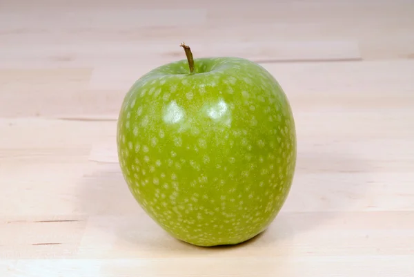 Manzana verde de granito en una mesa de madera — Foto de Stock