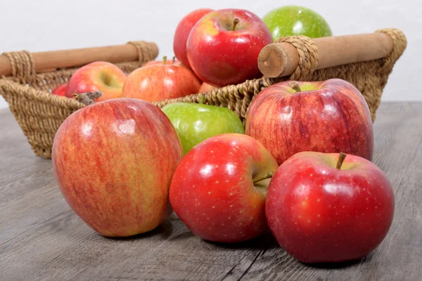 Olika äpplen i en flätad korg — Stockfoto