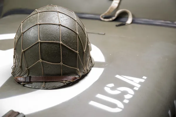 Military helmet on the hood of military vehicle — Stock Photo, Image