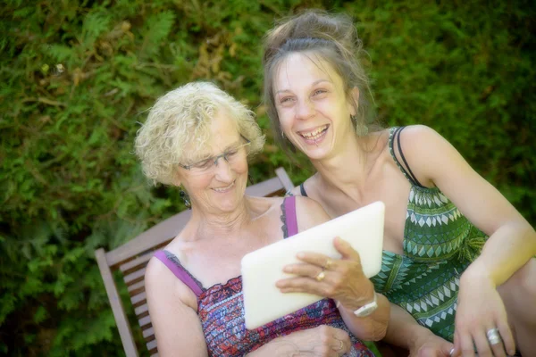 Mujer joven y su abuela mirando una tableta digital —  Fotos de Stock