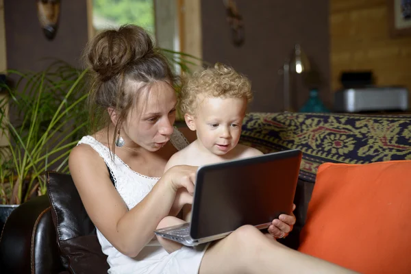 Jonge moeder en haar baby kijken naar de computer — Stockfoto