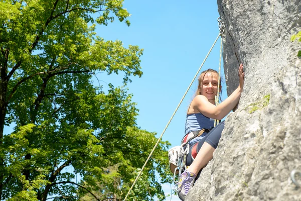 Jovem mulher escalando uma parede de rocha — Fotografia de Stock