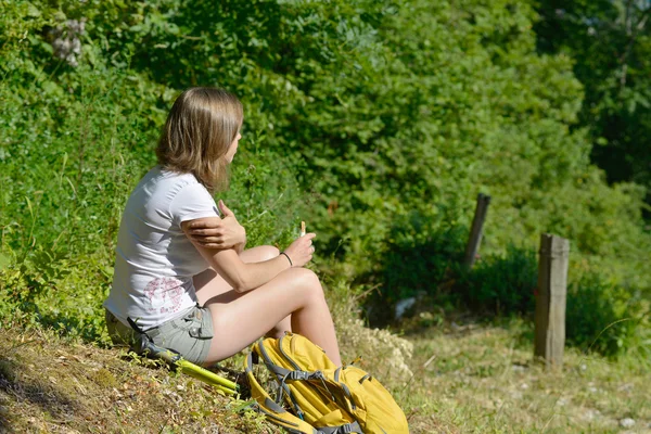 Hübsche junge Frau ruht sich während einer Bergwanderung aus — Stockfoto
