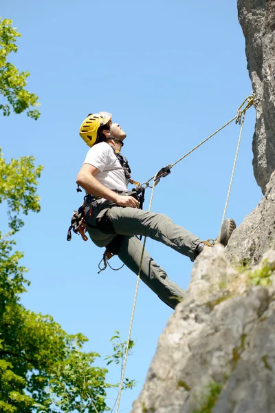 Young man climbing a rock wall — Stock Photo, Image